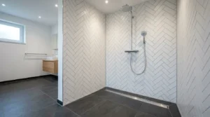 Silikonfugenarbeiten ausgeführt in bodengleicher Walk-in-Dusche mit weißen Fischgrätfliesen