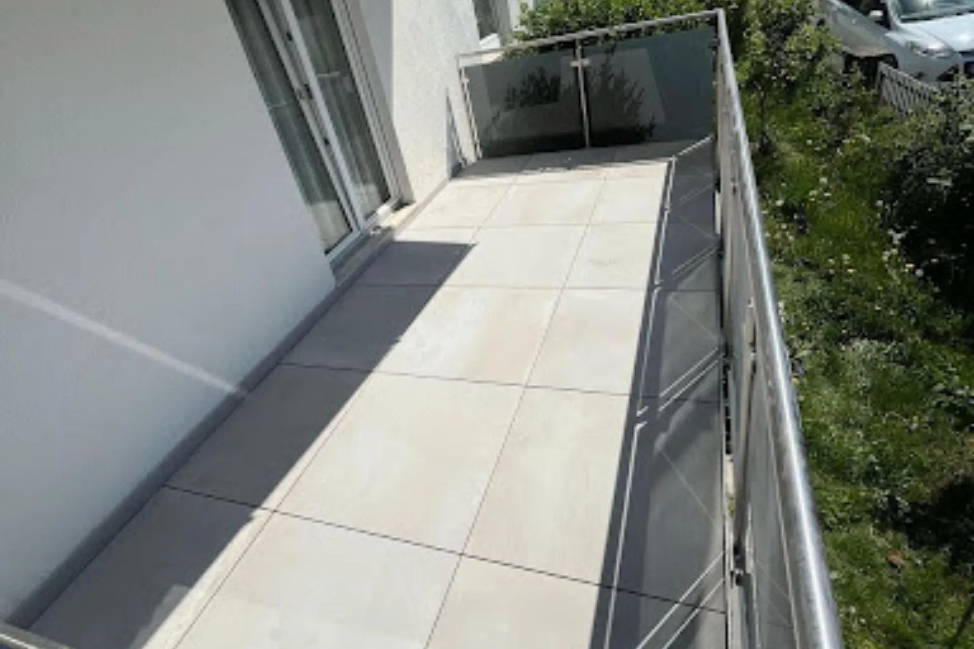 Helle Balkonfliesen sauber verlegt auf modernem Außenbalkon mit Glasgeländer