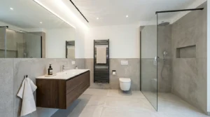 Modernes Bad ohne Fenster gestaltet mit bodengleicher Walk-in-Dusche, hellen Großformatfliesen und klarer Raumaufteilung