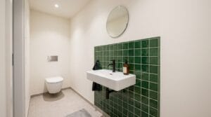 Kleines Waschbecken mit grünem Fliesenspiegel in einem modernen Gäste-WC als Fliesenspiegel im Bad